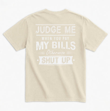  beige unisex graphic tee with white distressed typography on the back reading Judge Me When You Pay My Bills. Otherwise SHUT UP.