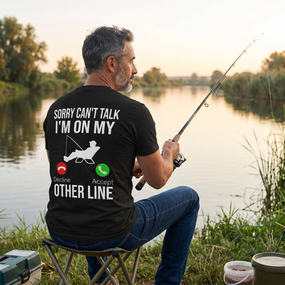  black cotton t-shirt with Sorry Can't Talk I'm On My Other Line fishing graphic worn by a man fishing