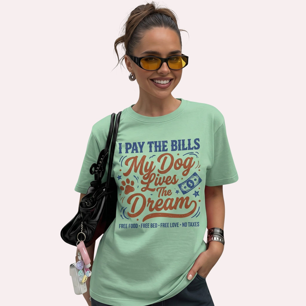  light green cotton t-shirt featuring I Pay The Bills My Dog Lives The Dream graphic on a smiling woman.