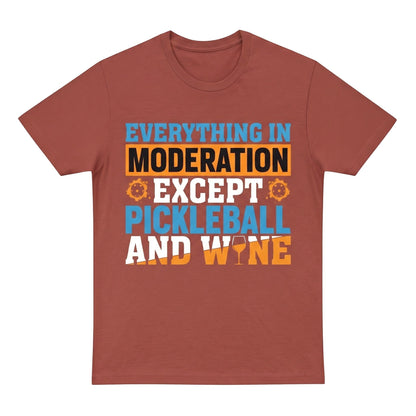  unisex cotton t-shirt in rust red with a blue and orange Pickleball and wine graphic print.