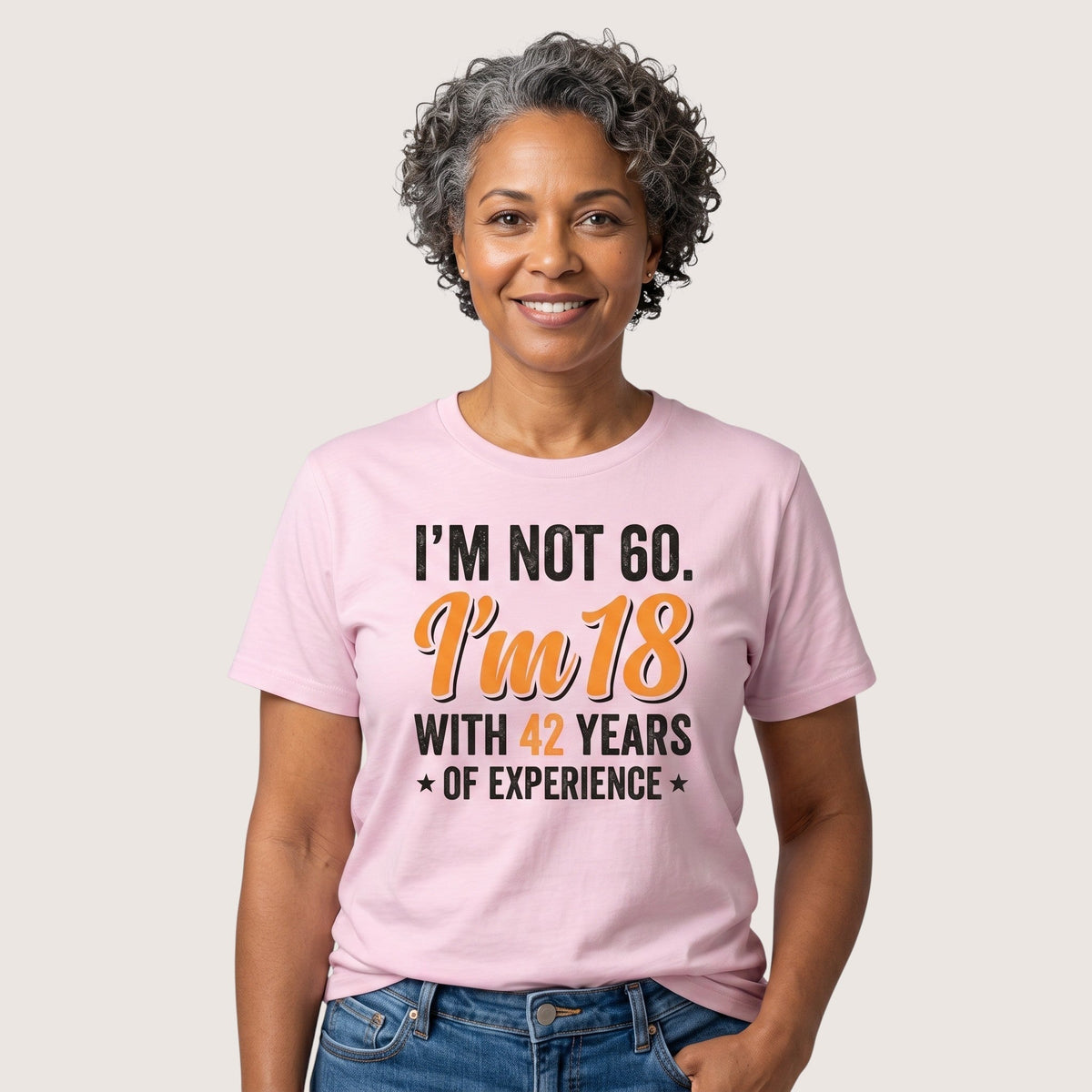  light pink cotton t-shirt with humorous 60th birthday quote worn by a smiling woman with grey hair.