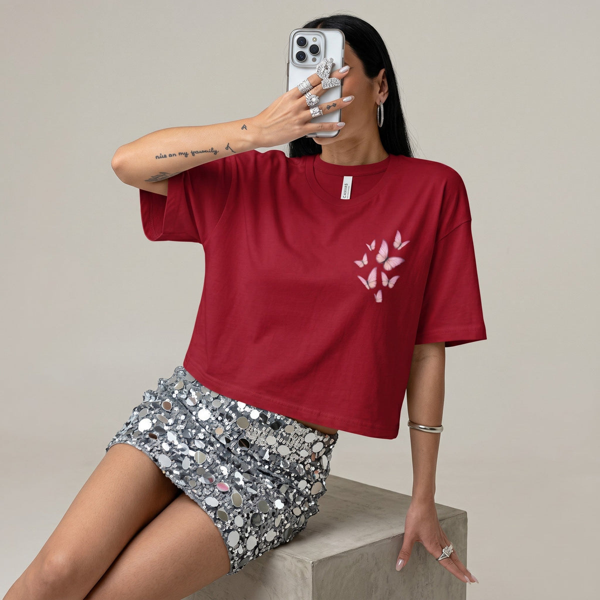  cropped red t-shirt with pink butterfly graphic, worn with a sequin mini skirt by a woman holding a phone