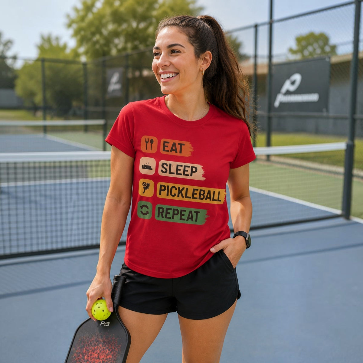  red cotton pickleball t-shirt with Eat Sleep Pickleball Repeat graphic worn by a smiling woman