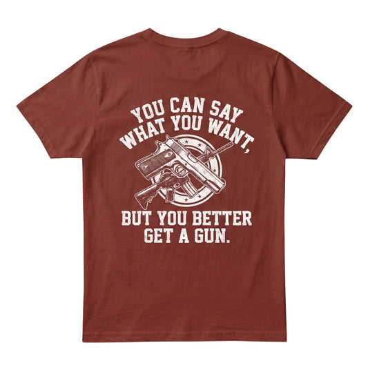  rust-colored cotton t-shirt featuring a white graphic print of firearms and bold text on the back.