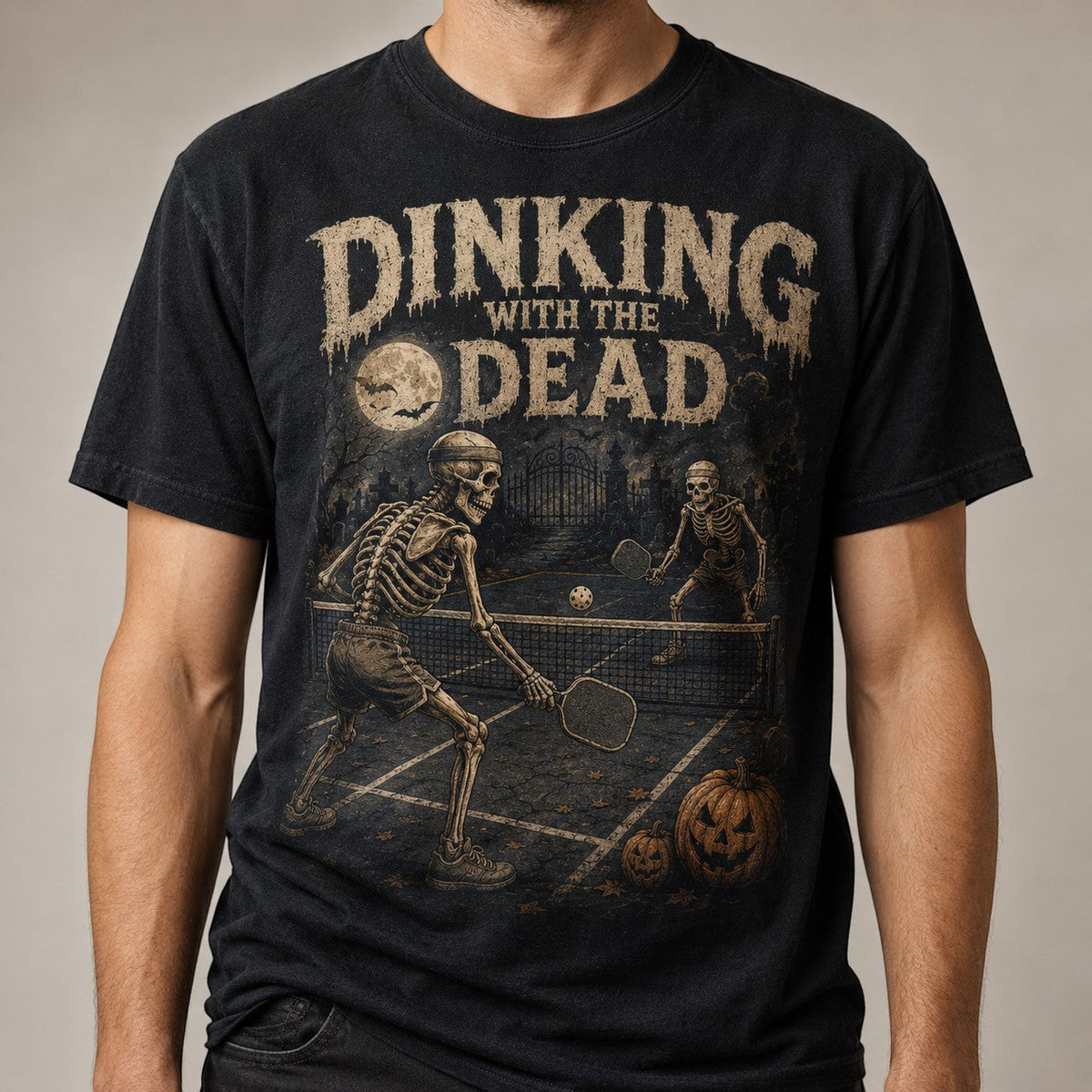 black t-shirt featuring skeletons playing pickleball with distressed vintage Halloween graphics.